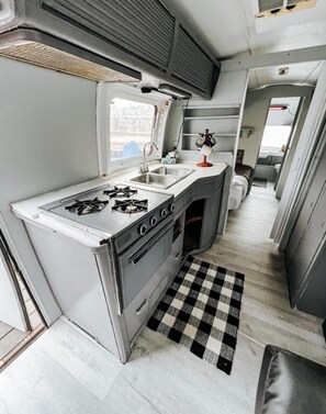 Compact kitchenette with gas stove, sink, and countertop, perfect for preparing meals on the go.