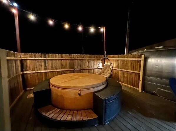 Relax in the hot tub surrounded by a deck and serene ambiance.