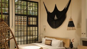 A room with a bed, a hammock, a checkered floor, and a view through a window with a grid pattern. - PAZ by DW (San Juan)