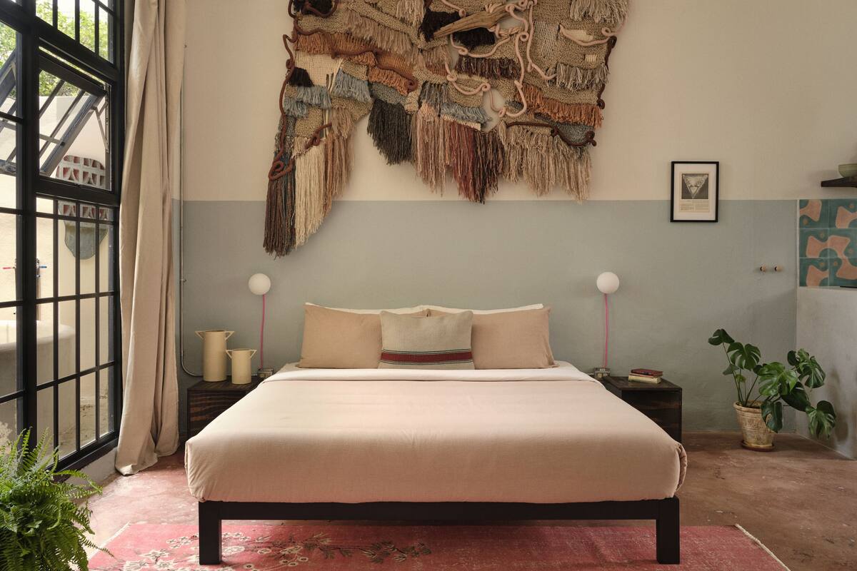 Une chambre avec un grand lit, une décoration murale et une fenêtre avec des rideaux.
