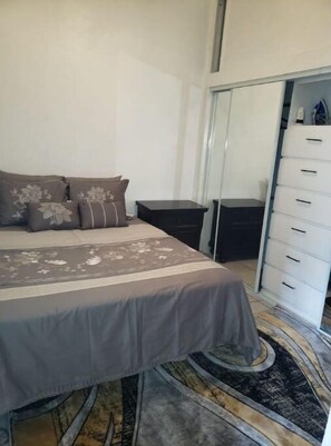 Cozy retreat with a neatly made bed, nightstand, and spacious wardrobe.