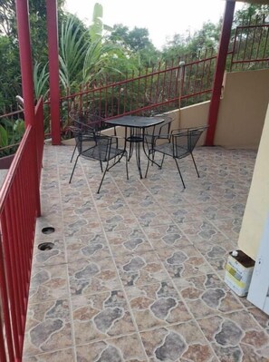 Enjoy a patio with a metal table and chairs, surrounded by lush greenery.