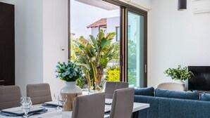 A dining area with a table set for two, a sofa, and a TV.