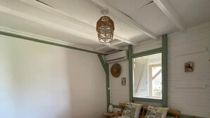Ett rum med en säng, ett litet bord, en hängande lampa och ett fönster.