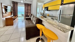 Une cuisine moderne avec des meubles de couleur jaune, un réfrigérateur en acier inoxydable et un coin bar équipé de deux tabourets.