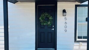 A black door with a wreath, a mailbox, and a number '5609' on the wall. - Tiny home in Watauga. “Casita”  Beautiful Cottage! (Watauga)