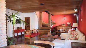 Una sala acogedora con techo de madera, una escalera y una pared roja decorativa.