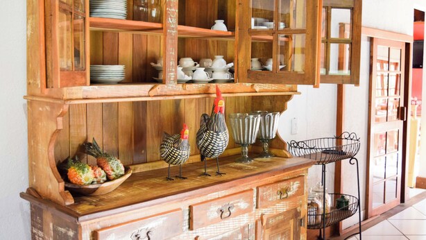 Un armario de madera con puertas de cristal que contiene vajilla y utensilios de cocina.