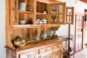A wooden cabinet with glass doors containing dishes and kitchenware. - Pousada Bela Cigana (Valenca)