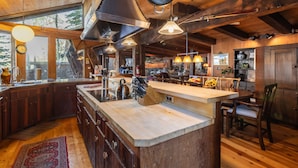 A spacious kitchen with wooden cabinets, a large island, and a rustic ceiling.