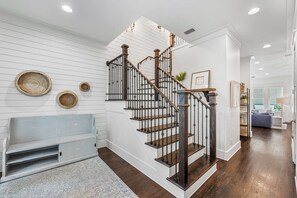 A staircase with wooden steps and black railings, a white wall with horizontal lines, and a blue bench.