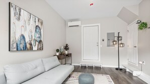 A modern living room with a white sofa, a colorful rug, and a large abstract painting on the wall. - Magnolia Sycamore by AvantStay | Near Downtown, Biltmore Estate, Hiking Trails (Asheville)