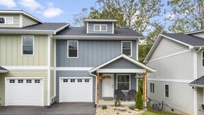 A two-story house with a front porch, two garages, and a small front yard with a mailbox and a potted plant. - Magnolia Sycamore by AvantStay | Near Downtown, Biltmore Estate, Hiking Trails (Asheville)