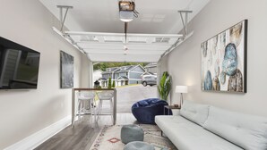 A modern living room with a white sofa, a blue bean bag, and a colorful rug. - Magnolia Sycamore by AvantStay | Near Downtown, Biltmore Estate, Hiking Trails (Asheville)