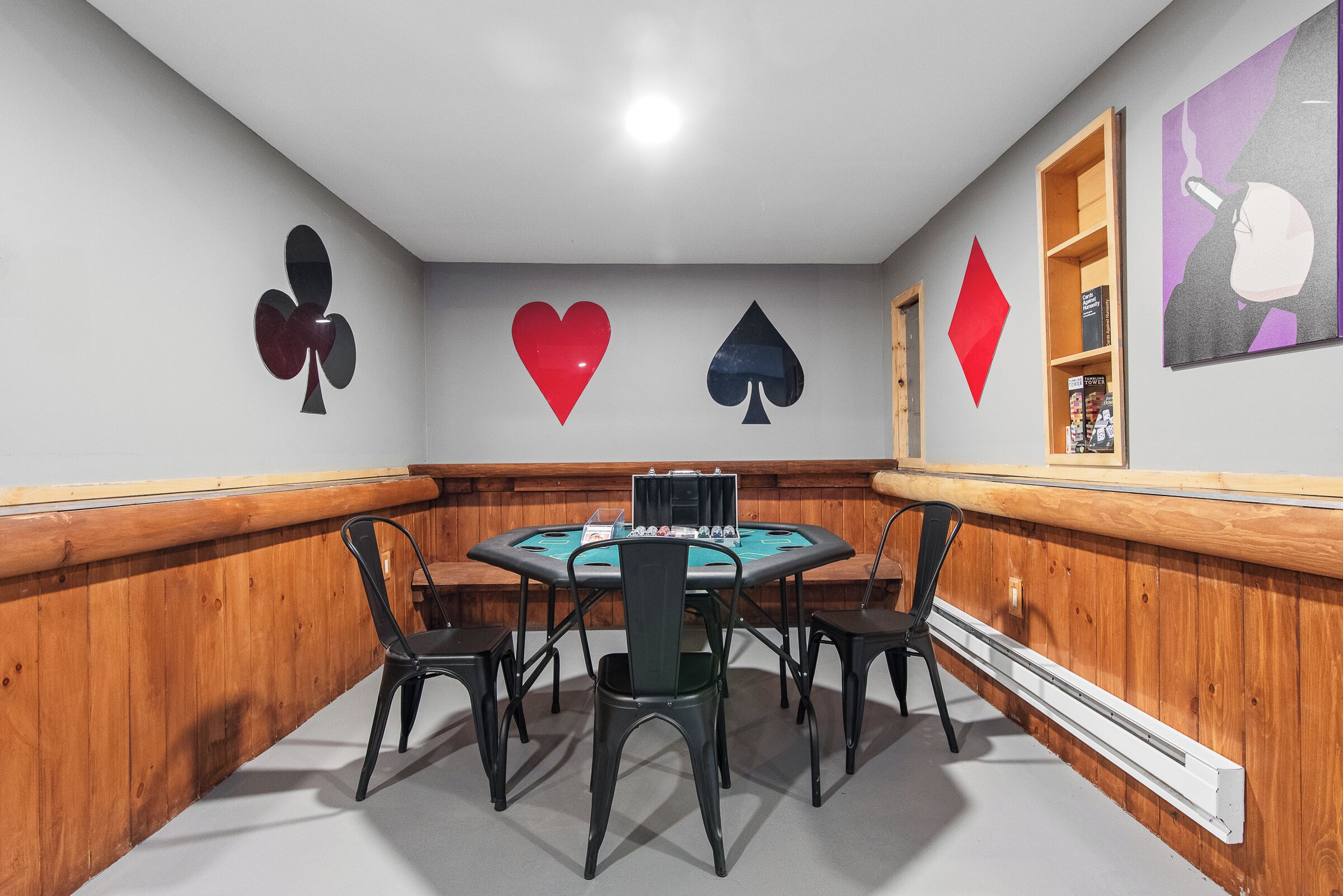 A room with a blackjack table, four chairs, and wall decorations including playing card symbols.