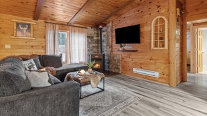 Een gezellig interieur van een chalet met een open haard, een bank en een televisie.