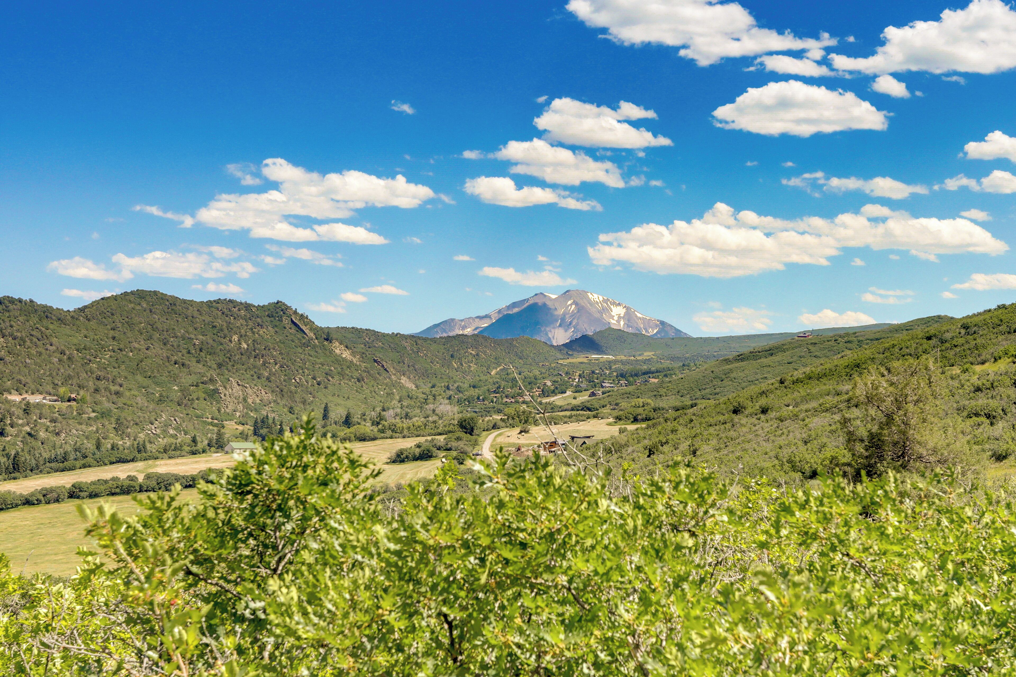Eine gebirgige Landschaft mit blauem Himmel und vereinzelten Wolken.