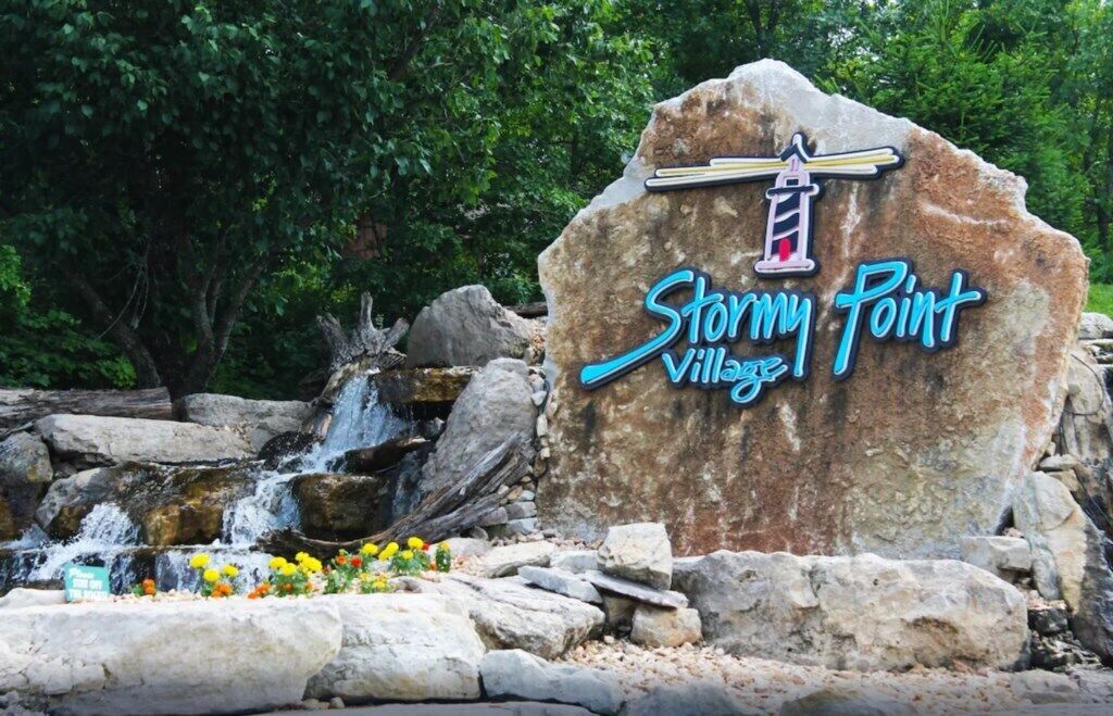 A large rock with the text "Stormy Point Village" and a lighthouse graphic.