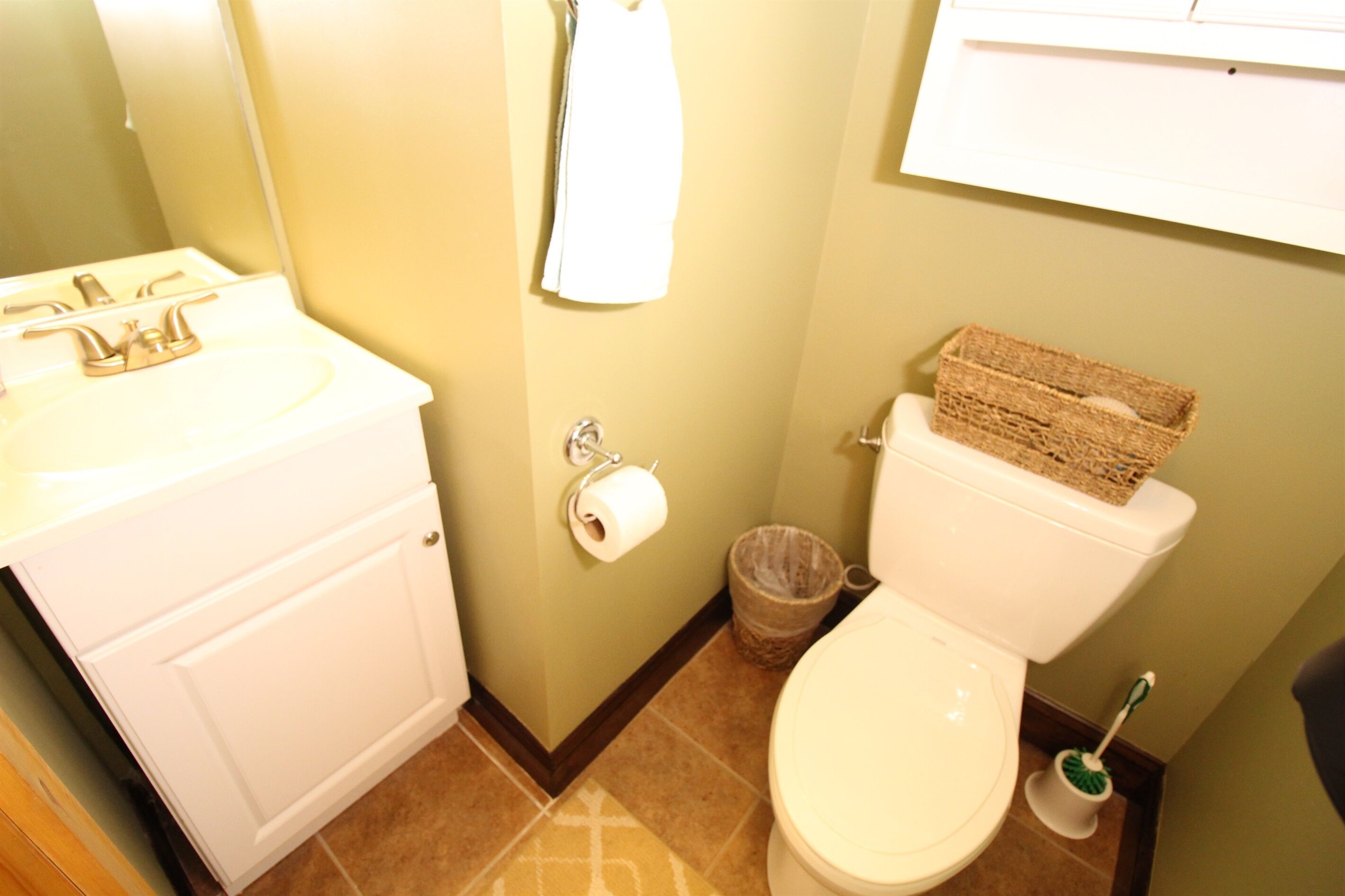 Un baño con lavamanos blanco, inodoro y cubo de basura.