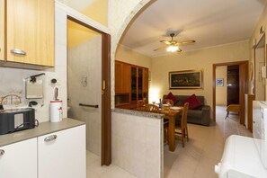 Una cucina accessoriata con tostapane, macchina del caffè e frigorifero. C'è un'area pranzo con tavolo e sedie.