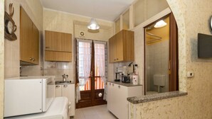 A compact kitchen with wooden cabinets, a microwave, a coffee maker, and a sink.