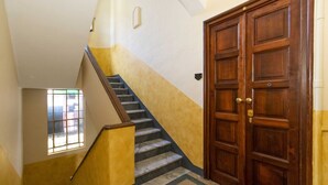 A staircase with a wooden handrail, a door with a brass handle, and a window with bars.