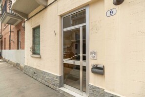 A building with a glass door entrance, a number '9' sign, and a mailbox. - GuestHost - MM Massaua Apartment - w/ two Balconies (Torino)
