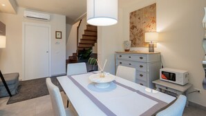 A dining area with a table, chairs, a hanging light fixture, a microwave, and a staircase. - GuestHost - Cozy and modern 65 sqmapartment, on two levels, able to accommodate up to 6 people, located on the ground floor of a building (a few steps to access). The property is located in a quiet area, about 500 meters from Piazza della Libertà, and w (Firenze)