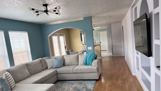 Ein Wohnzimmer mit einem Ecksofa, einem Deckenventilator und einem an der Wand befestigten Fernseher.