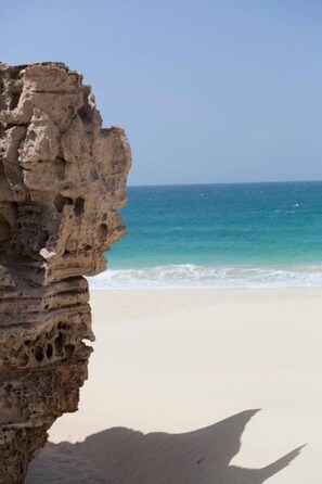 A coastal scene with a rocky cliff and a beach.