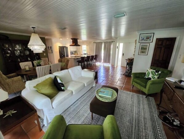 Relax in this inviting living area with a sofa, armchair, and coffee table, surrounded by a kitchen and dining space.