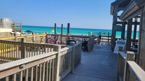 Un paseo marítimo de madera que conduce a una playa, con un letrero que indica Emerald Shores.