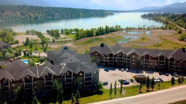 Ein mehrstöckiges Hotel mit Parkplatz und Blick auf einen See und Berge.
