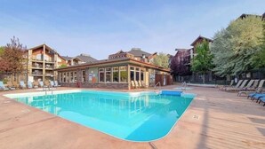 Ein Schwimmbecken mit Liegestühlen und ein mehrstöckiges Gebäude mit großen Fenstern.