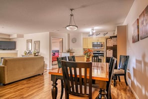 Relax in a spacious living area with a dining table and sofa, surrounded by modern kitchen amenities.