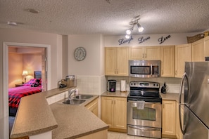 Kitchen features a stainless steel refrigerator, microwave, and double oven, with wooden cabinets and a granite countertop.