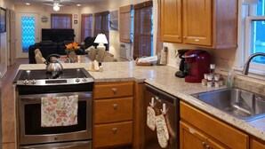 A kitchen with wooden cabinets, a stainless steel stove, and a large window. - A Sandcrab & Jellyfish Walk Into a Sand-Bar (Ocean City)