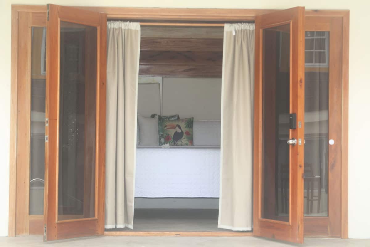 A room with a bed, a pillow with a bird design, and a door with glass panels.
