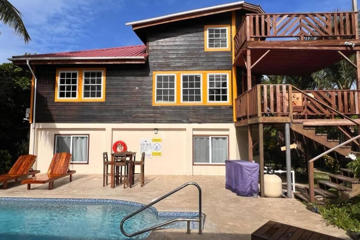 A two-story wooden building with a swimming pool, outdoor seating, and a covered area.