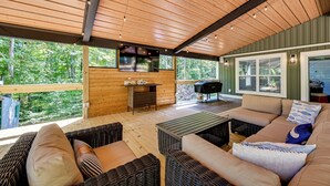 A covered outdoor seating area with wicker furniture, a flat-screen TV, and a barbecue grill. - Luxe Kentucky Cabin Rental ~ 36 Mi to Mammoth Cave (Cub Run)