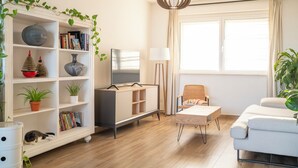 A modern living room with a white sofa, a TV, a bookshelf, and a dining area. - Villa Celestina (Marco Simone)