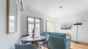 A modern living room with a round wooden table, two grey chairs, a teal sofa, and a black floor lamp. - GuestReady -  Downtown refuge with charm (Porto)