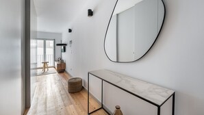 A modern hallway with a marble console table, a large oval mirror, and a floor lamp. - GuestReady -  Downtown refuge with charm (Porto)