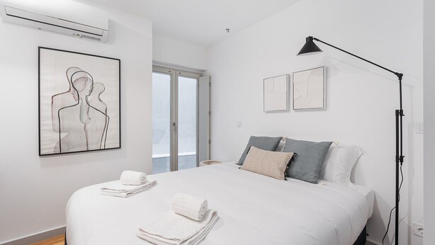 A bedroom with a bed, pillows, a floor lamp, and artwork on the wall. - GuestReady -  Downtown refuge with charm (Porto)