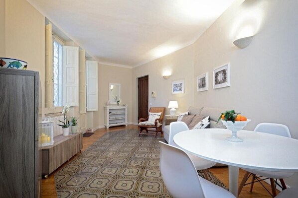 Un coin repas comprenant une table ronde, des chaises, un tapis à motifs et un buffet.