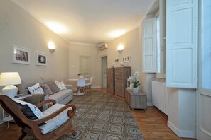 Un salon chaleureux avec un canapé, une chaise en bois, un tapis à motifs, une petite table avec des chaises et un meuble.