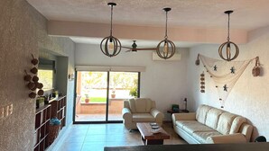 A spacious living room with a sofa, a coffee table, and a TV. There are decorative baskets on the wall and a ceiling fan. - Amplio Depa en San José del Cabo, Zona Hotelera, Hasta 8 Personas, Alberca (San José del Cabo)
