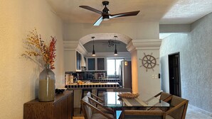 A modern kitchen with a central island, a dining area with a glass table, and a ceiling fan. - Amplio Depa en San José del Cabo, Zona Hotelera, Hasta 8 Personas, Alberca (San José del Cabo)