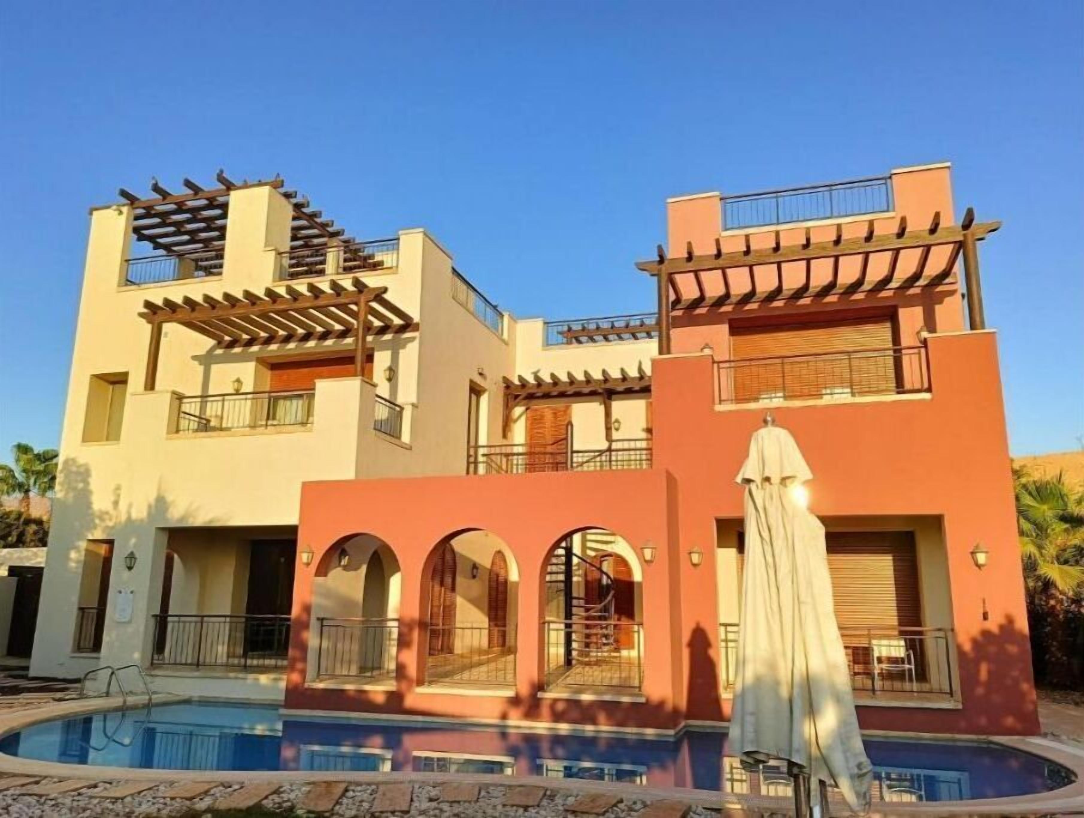 Um edifício moderno de dois andares com piscina em frente.