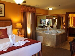 Relax in a spacious room with a large bed and a separate bathroom featuring a bathtub and mirror.